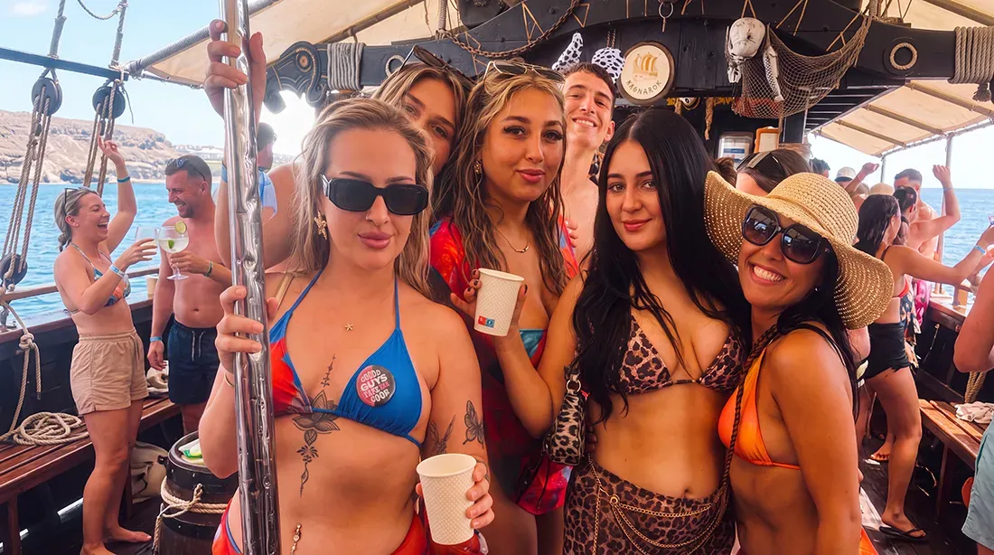 Group of smiling guests posing on sailing boat deck during daytime party