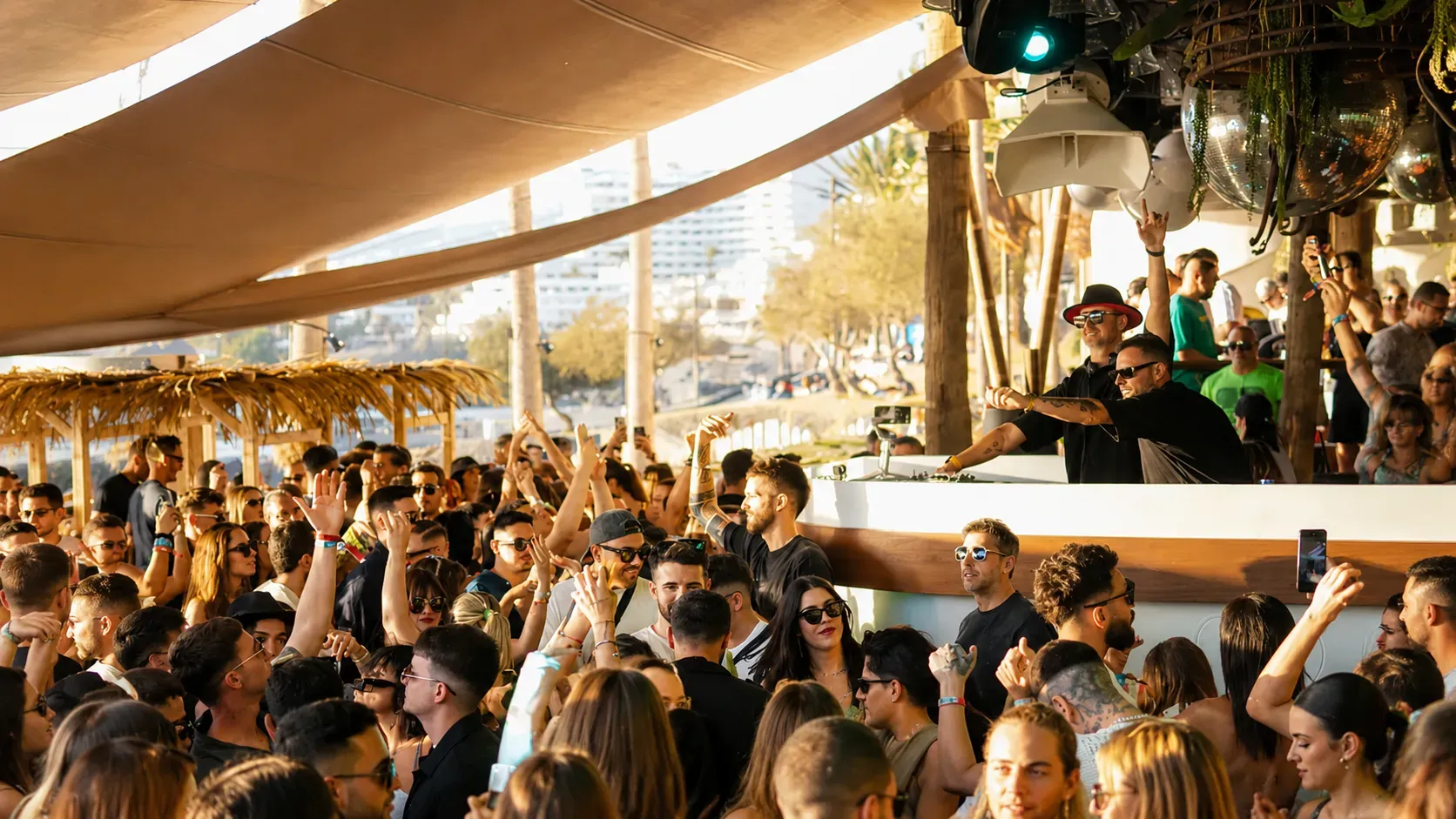 Large crowd of guests dancing and celebrating under shaded deck area on boat party