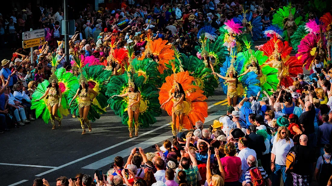 Colorful carnival parade with feathered dancers and street spectators in Tenerife