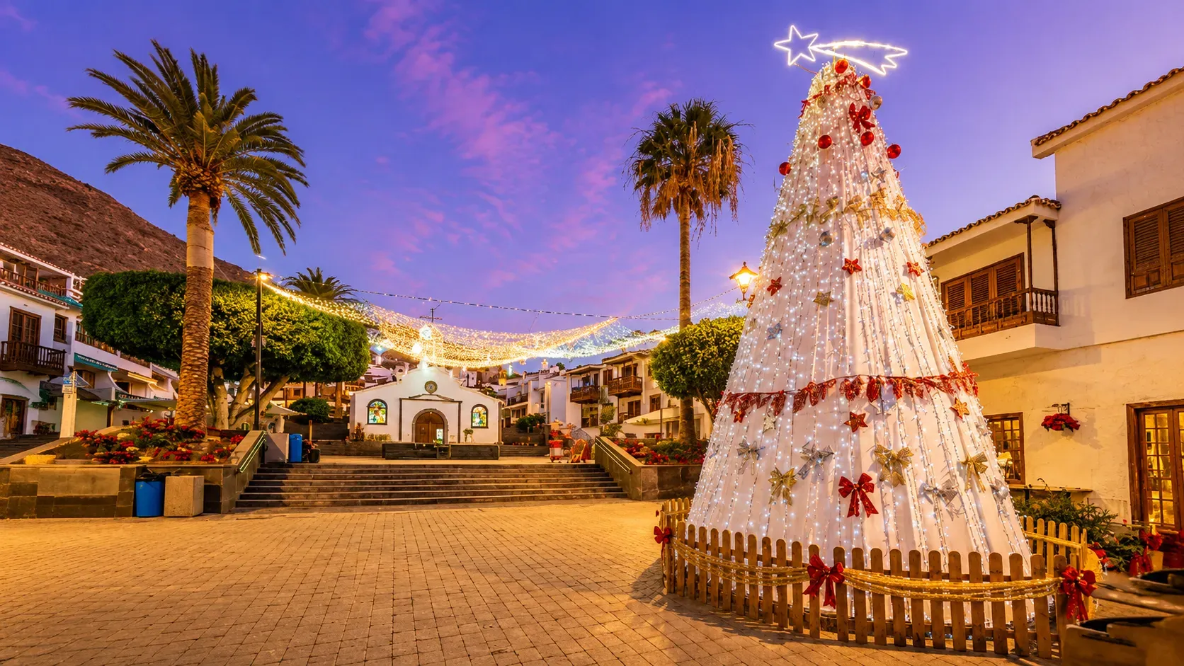 Christmas tree decorated with lights and red bows in colonial town plaza