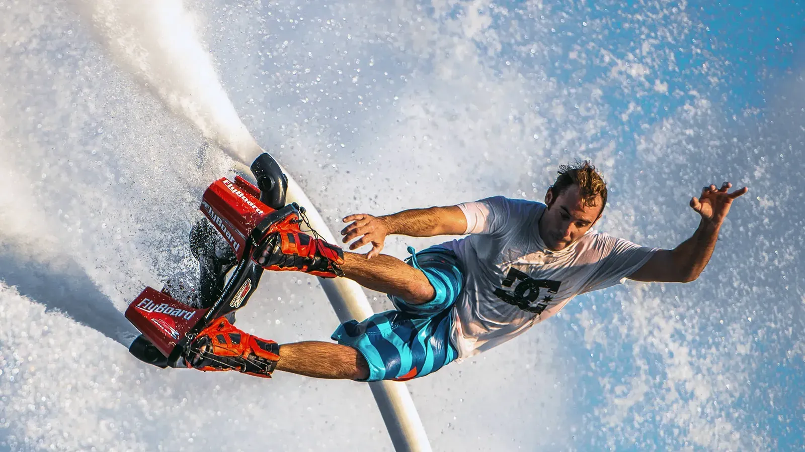 Wakeboarder in mid-air performing trick behind boat in ocean