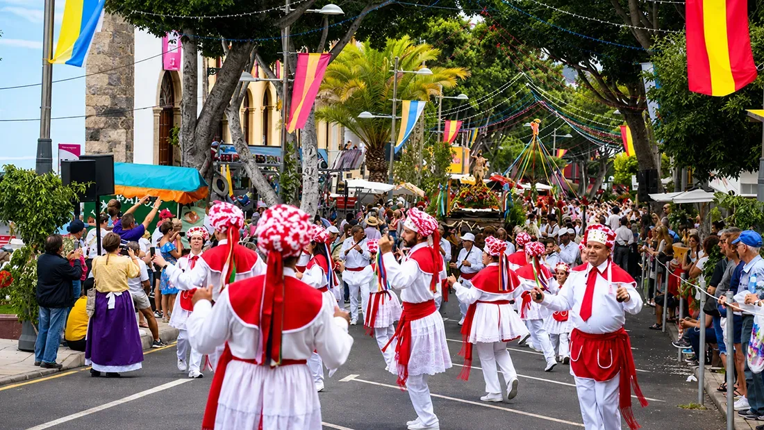 Colorful street parade with red and white costumed performers marching through decorated town square