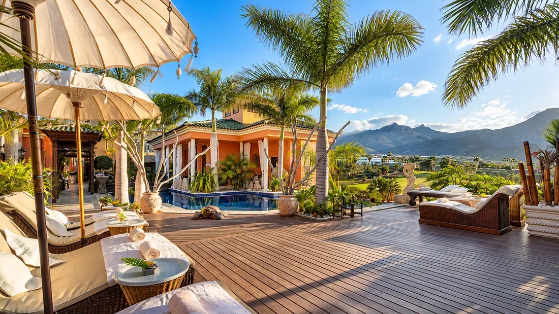 Luxury resort terrace with pool, umbrellas, and mountain views