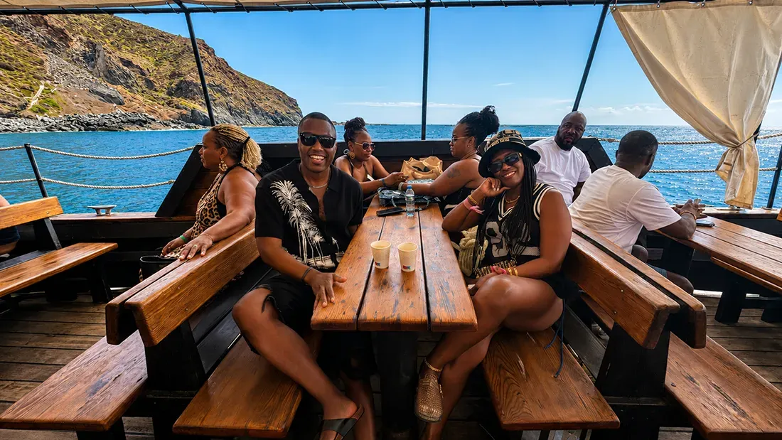 Group of guests enjoying drinks on wooden benches during boat tour