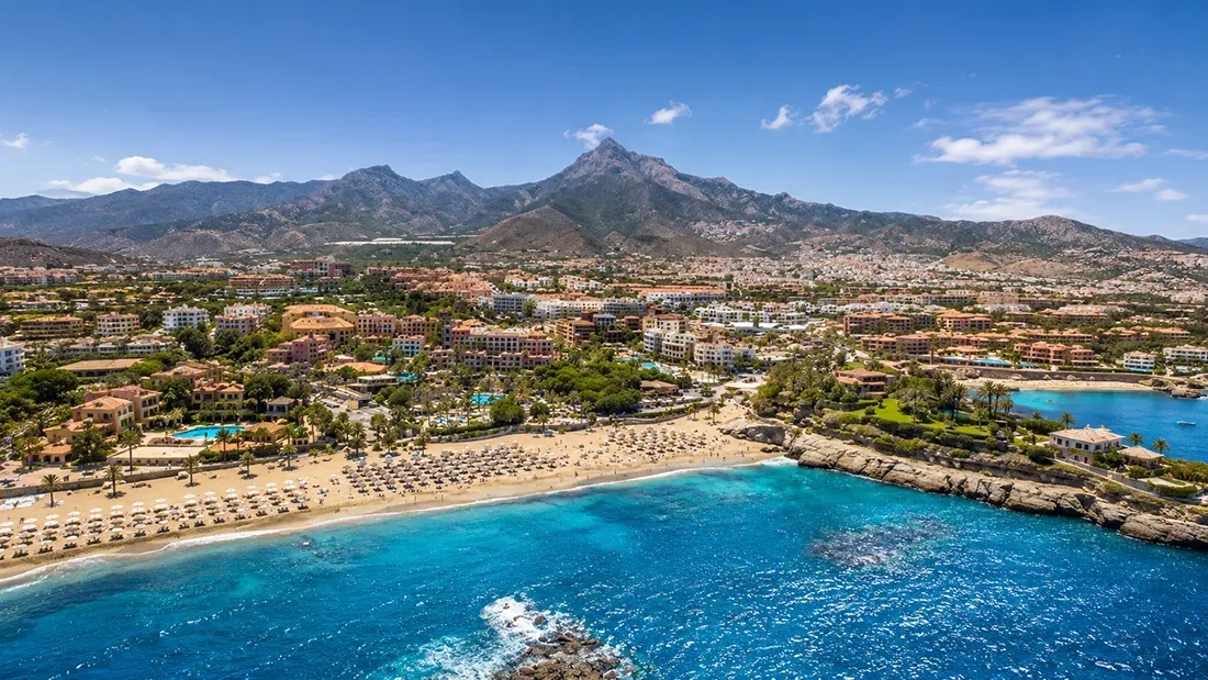 Coastal resort town with beach, mountains, and turquoise Mediterranean water