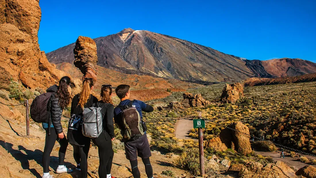 Group of hikers viewing Mount Teide volcano from rocky trail