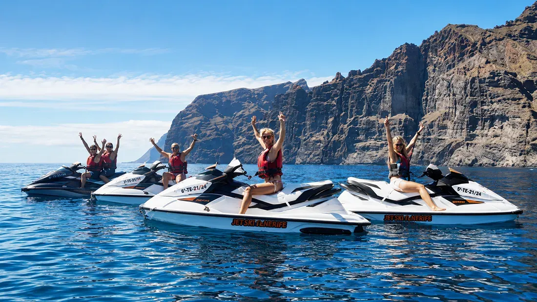 Group celebrates on jet skis near dramatic coastal cliffs