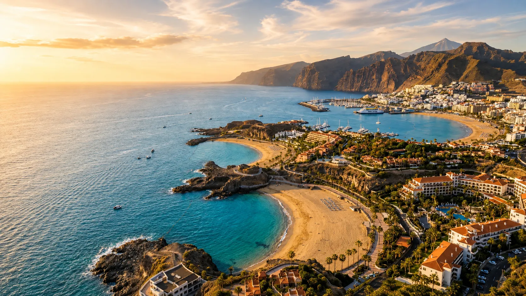 Aerial view of Tenerife coastal town with golden beaches and anchored boats