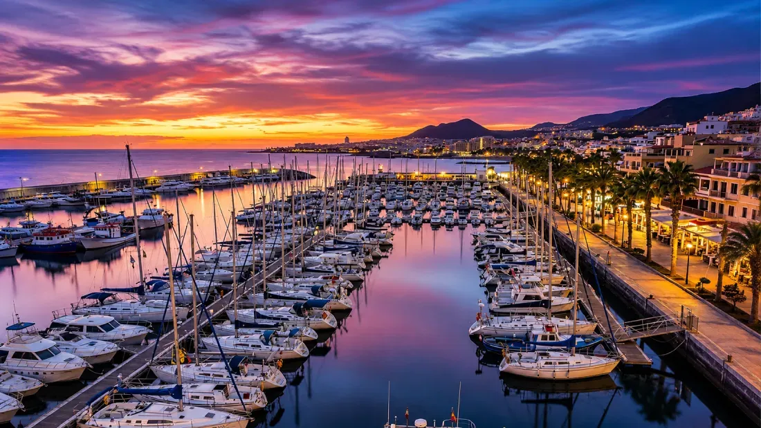 Marina at sunset with sailboats and coastal buildings, Tenerife