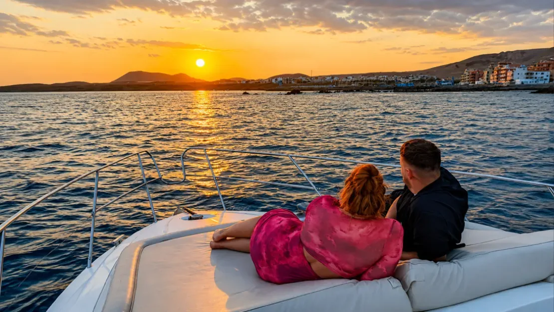 Couple relaxing on boat deck watching sunset over Tenerife coastline