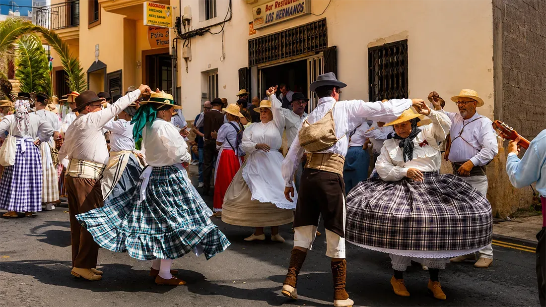 # Alt Text
Group in traditional Canarian dress dancing in colonial street celebration