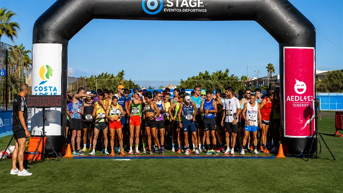 Runners lined up at start line under inflatable race arch gate